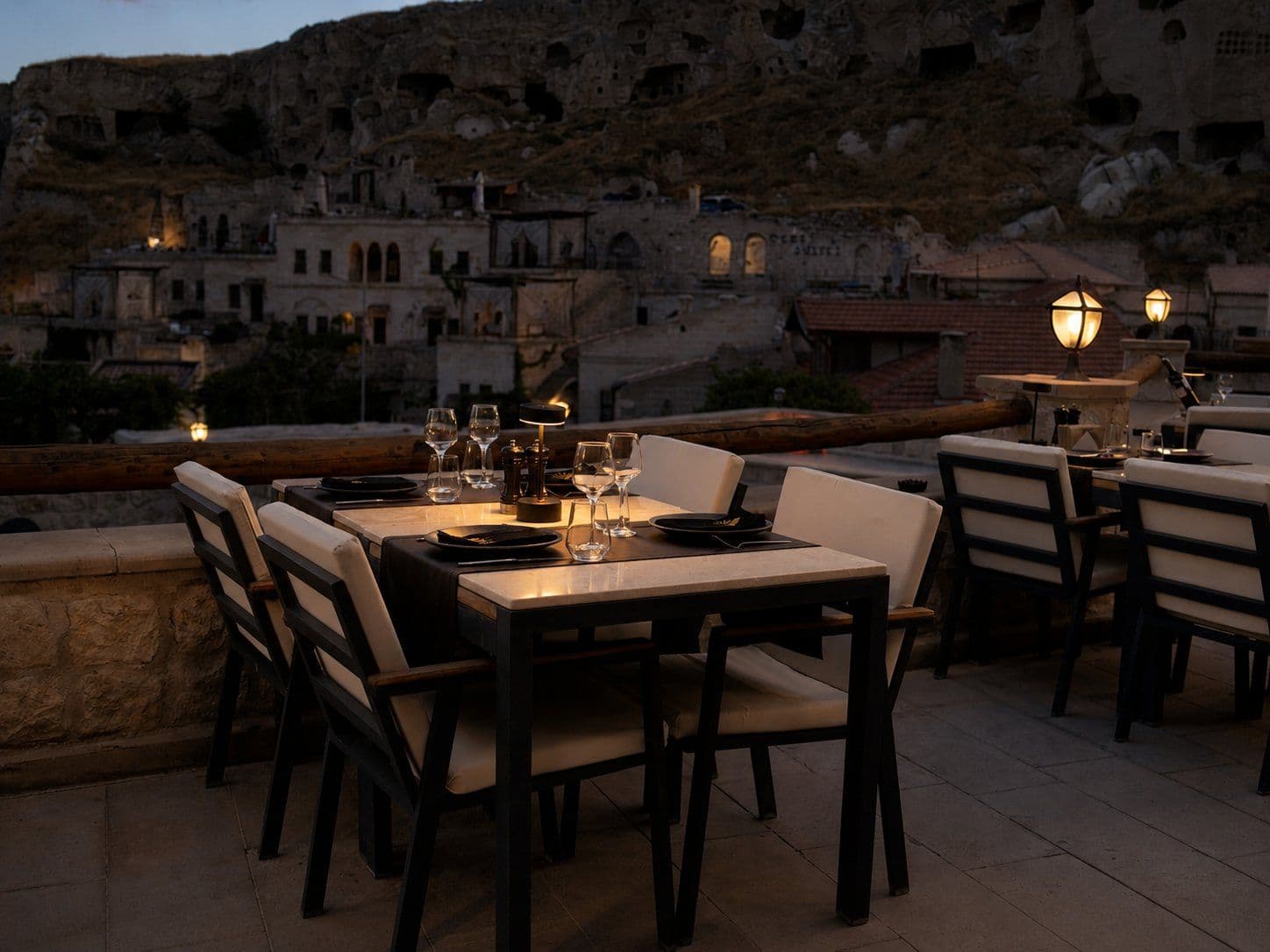A set table on the Solem Restaurant terrace at sunset, cave cliffs behind